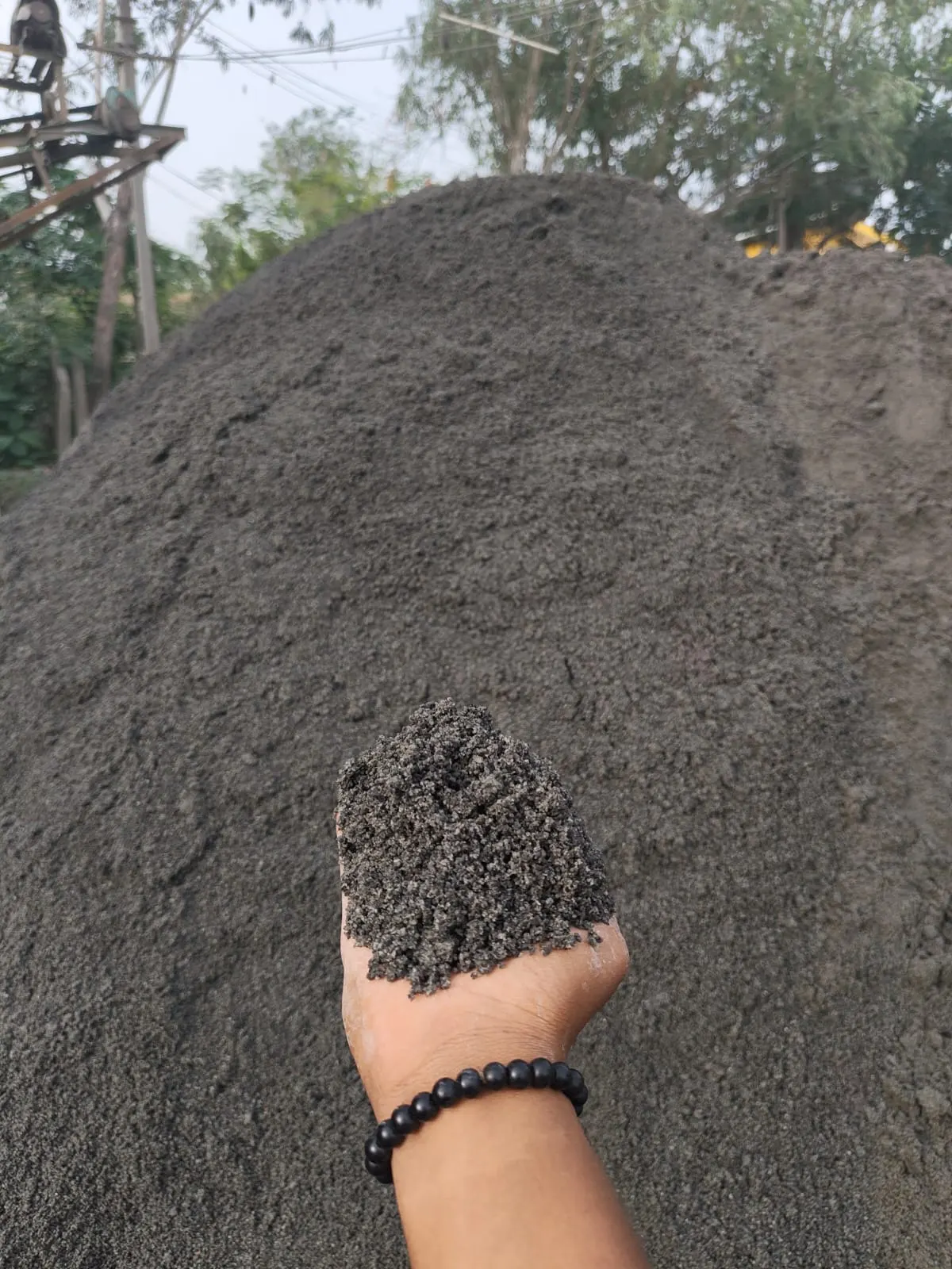 Washed M-Sand on a hand-held pile, dark grey granite fines